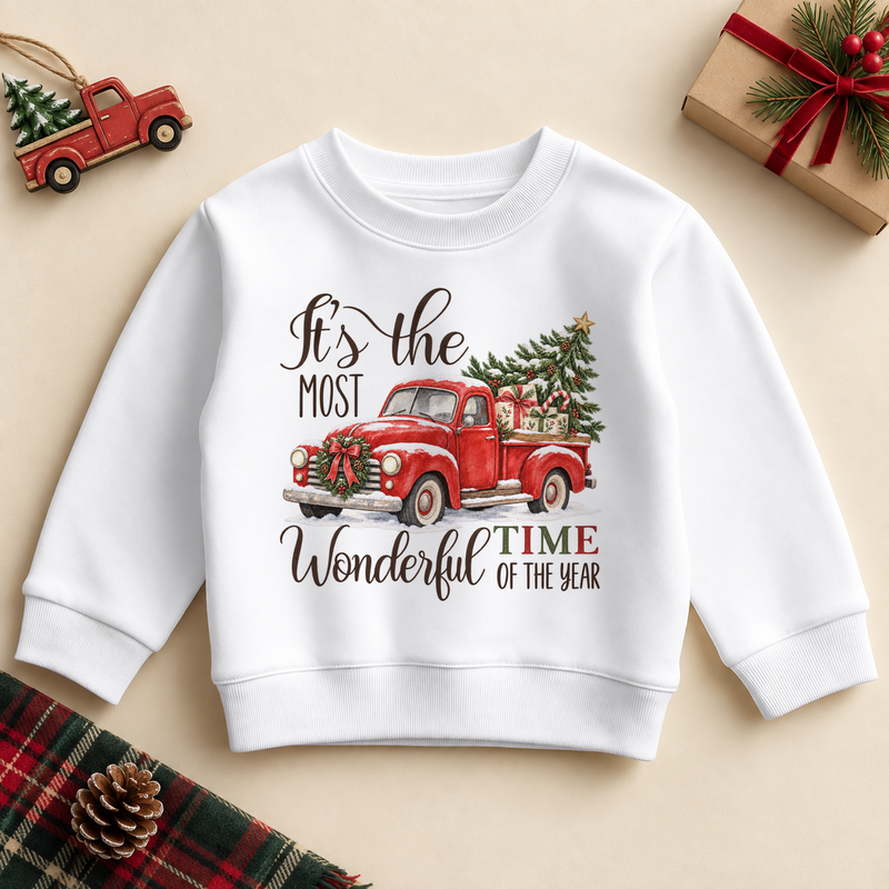 White kids sweatshirt with a red vintage pickup carrying a Christmas tree, with festive lettering. It's the most wonderful time of the year wording.