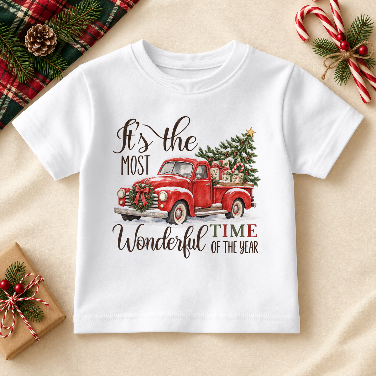 White kids T-shirt with a red vintage pickup carrying a Christmas tree, with festive lettering. It's the most wonderful time of the year wording.