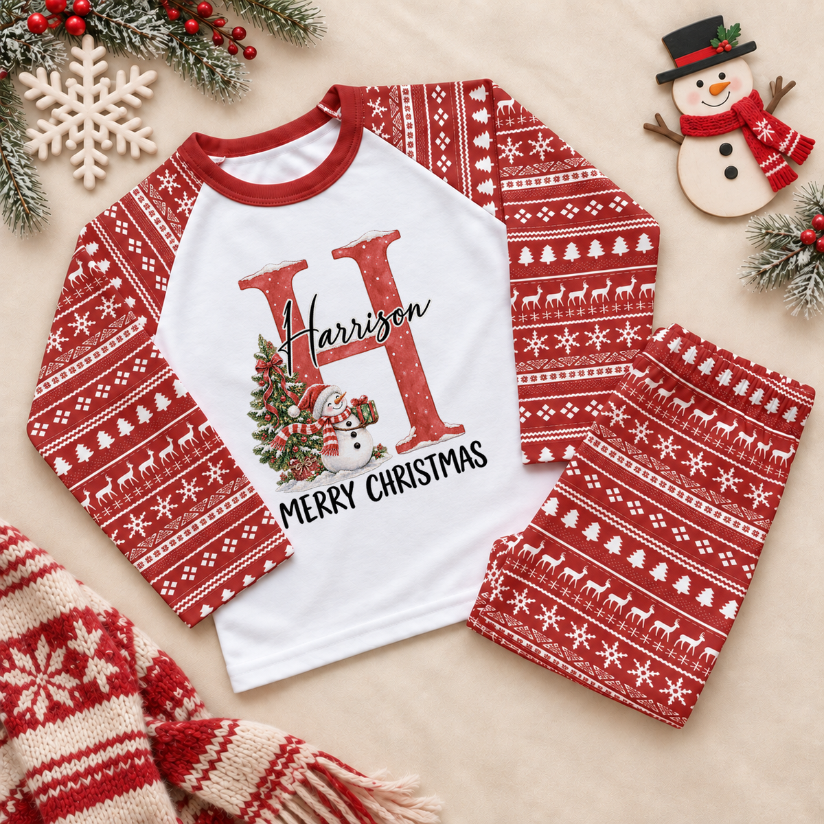 Red and white pyjama set. The print features a red initial beside a snowman and a decorated Christmas tree.