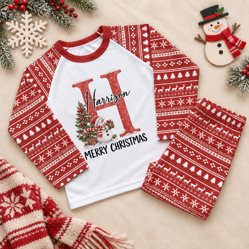 Red and white pyjama set. The print features a red initial beside a snowman and a decorated Christmas tree.