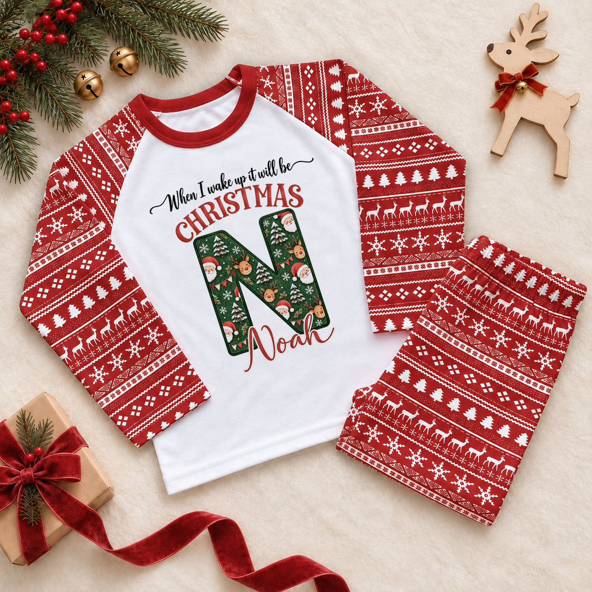Red and white pyjama set. The print features a deep green initial filled with Santa, reindeer and snowy Christmas details.