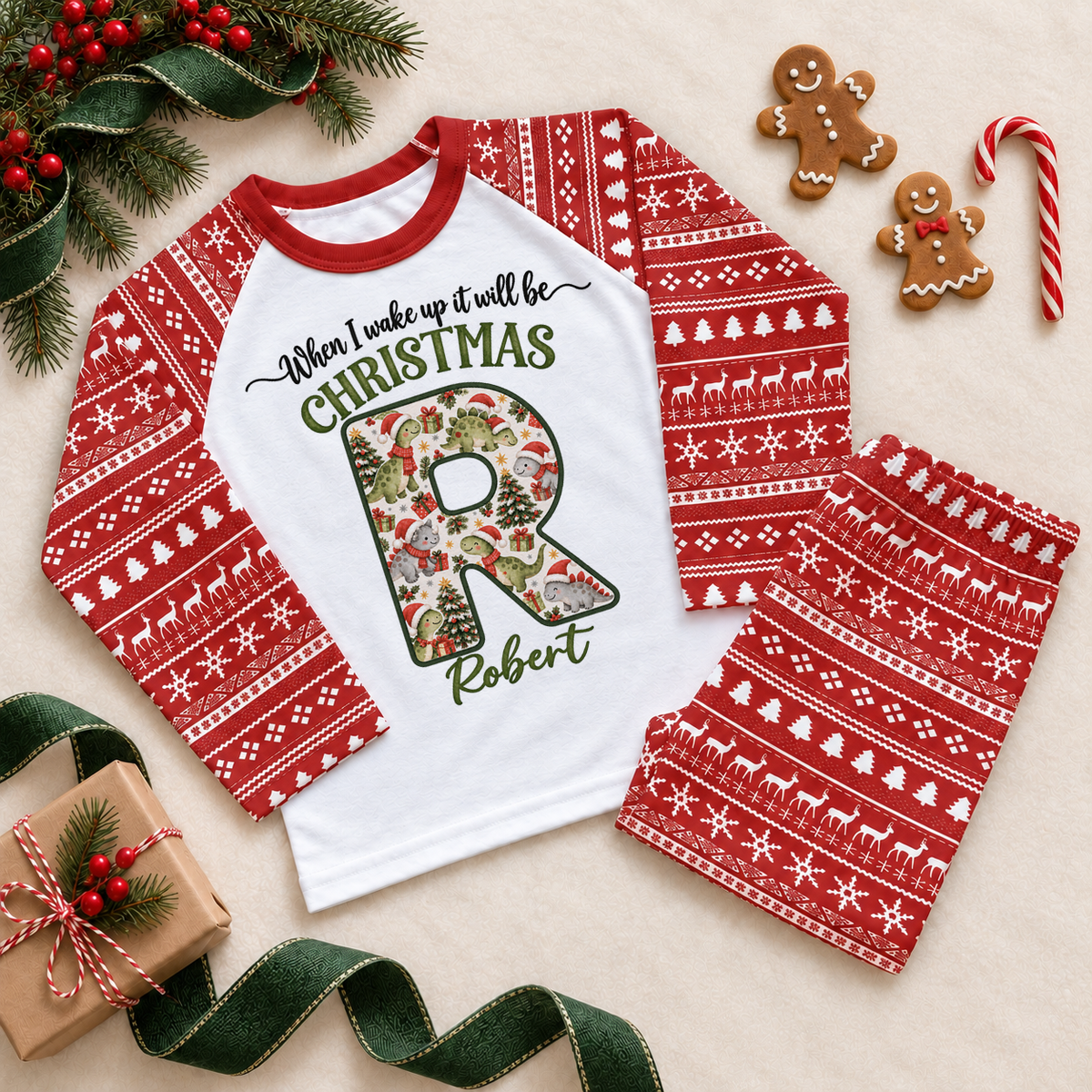 Red and white pyjama set. The print features a cream initial filled with little dinosaurs in festive hats and scarves.