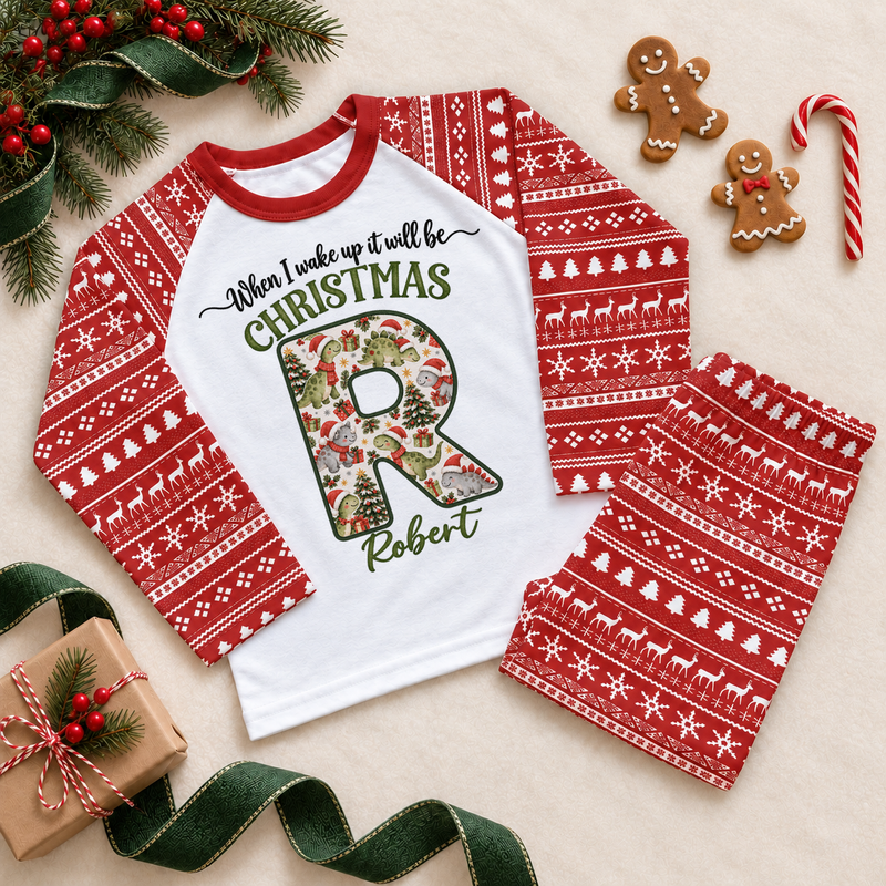 Red and white pyjama set. The print features a cream initial filled with little dinosaurs in festive hats and scarves.