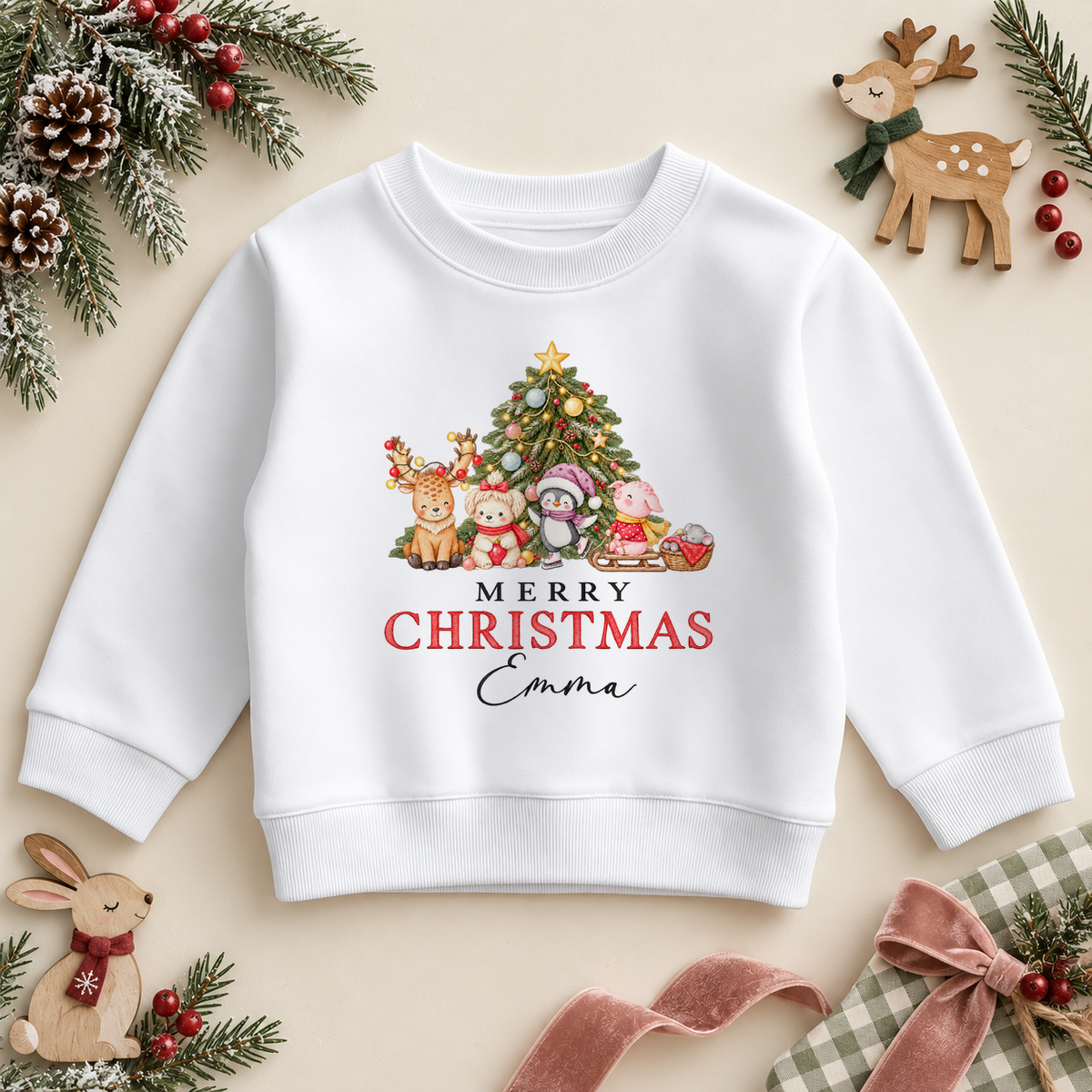 White children's sweatshirt with a Christmas tree, reindeer, teddy, penguin, pig and mouse, plus Merry Christmas lettering and the example name Emma.