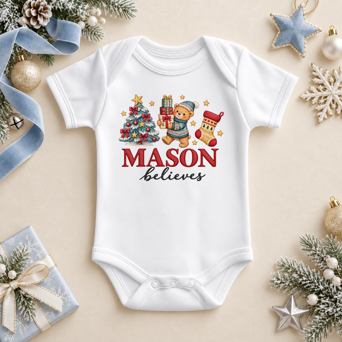 White baby bodysuit. The print features a teddy in a blue hat holding gifts beside a decorated tree and Christmas stocking.