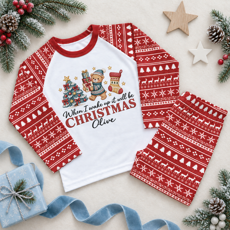 Red and white pyjama set. The print features a teddy in a blue hat holding gifts beside a decorated tree and Christmas stocking.