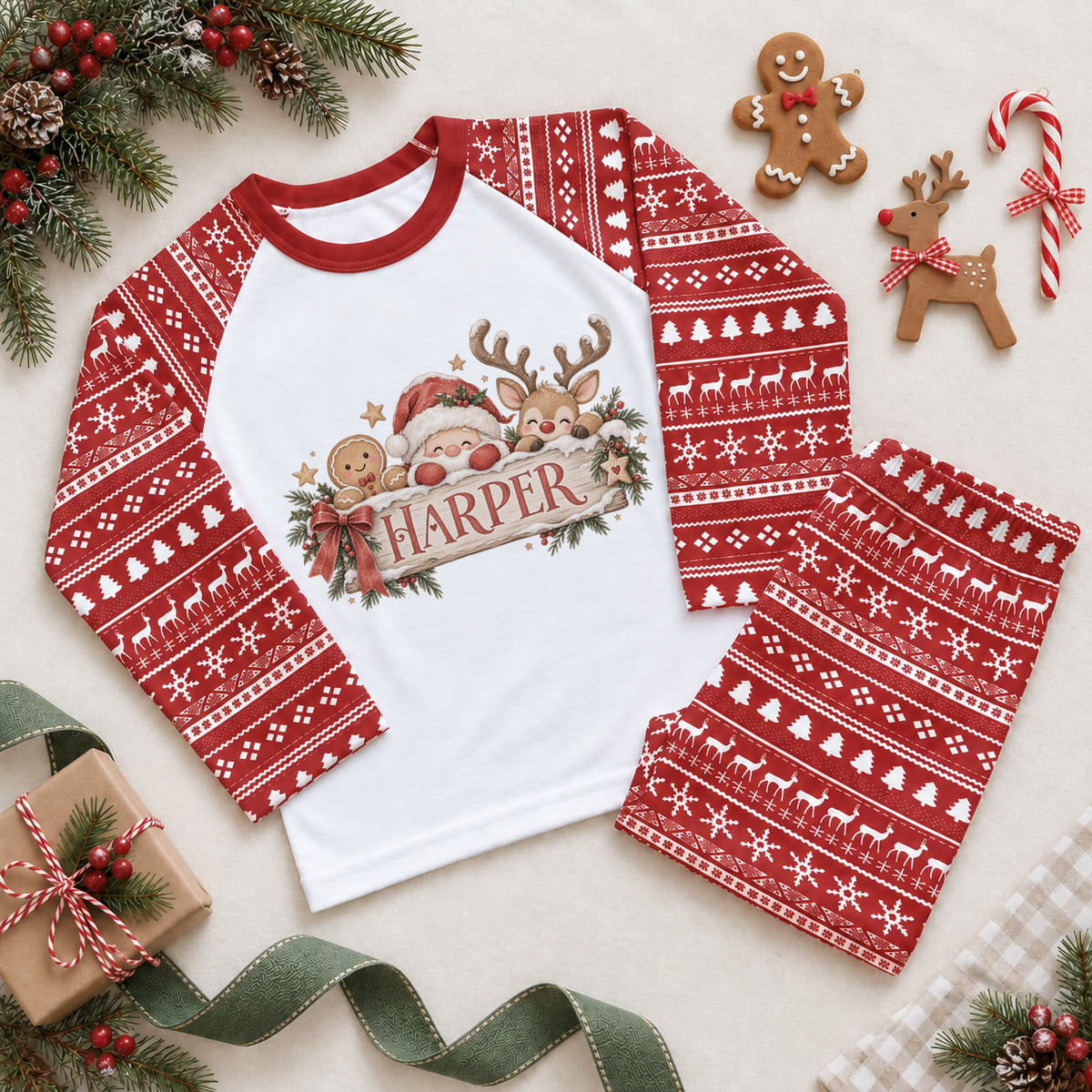 Red and white pyjama set. The print features Santa, a reindeer and a gingerbread character peeking over a festive name sign.