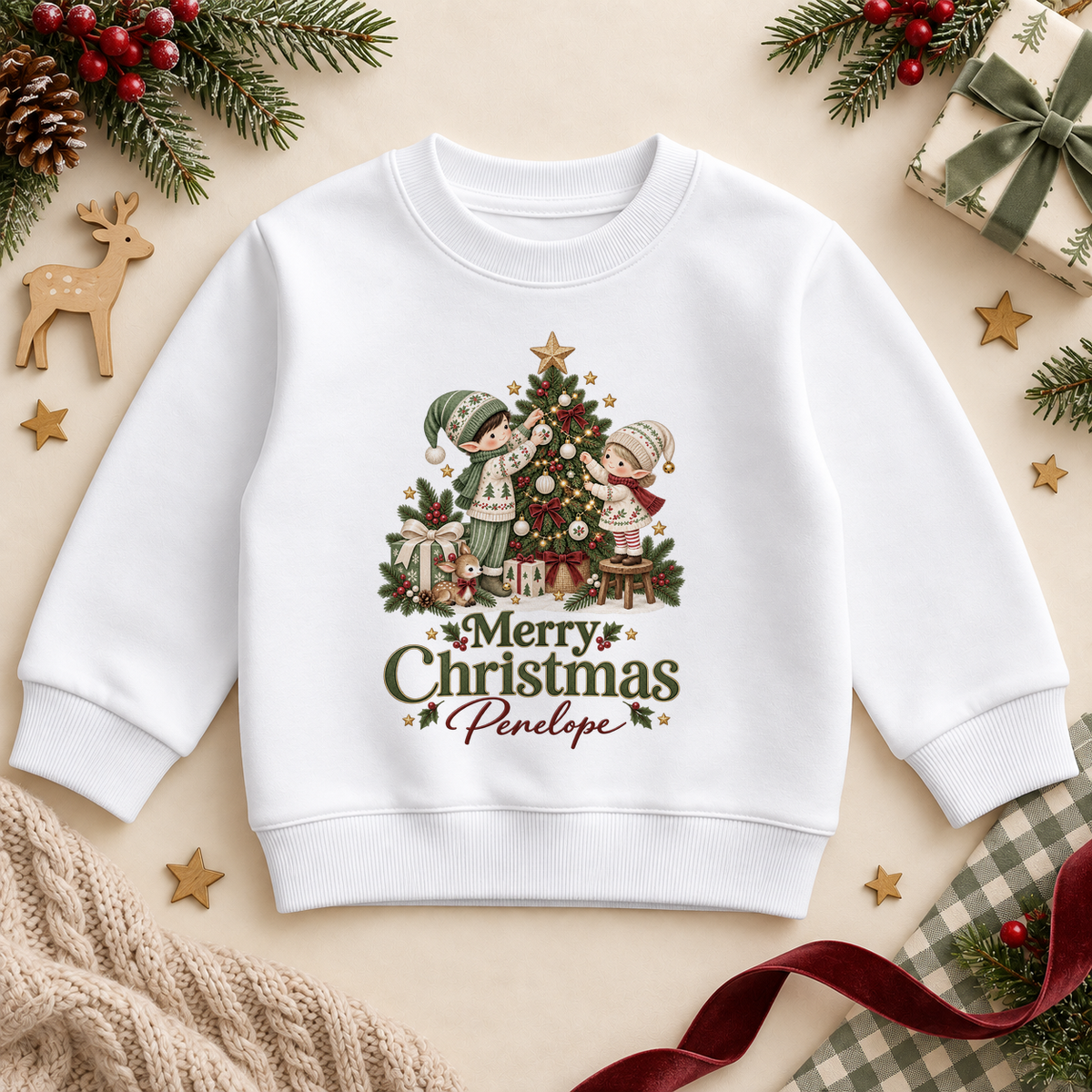 White children’s sweatshirt. The print features two elves decorating a Christmas tree, surrounded by ribboned presents.