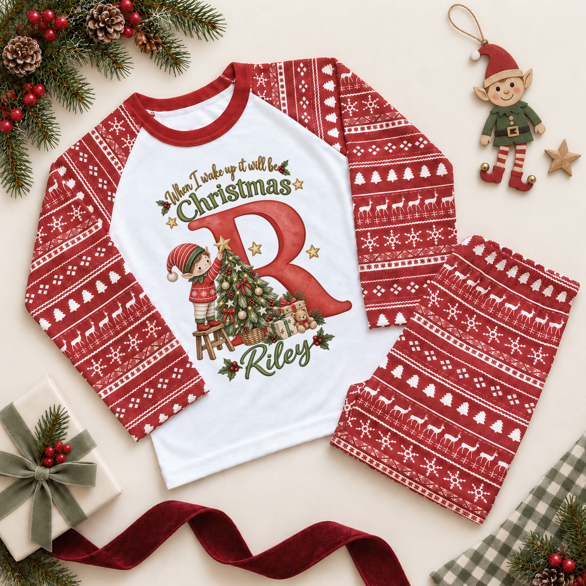 Red and white pyjama set. The print features a red initial with a little elf decorating a Christmas tree.