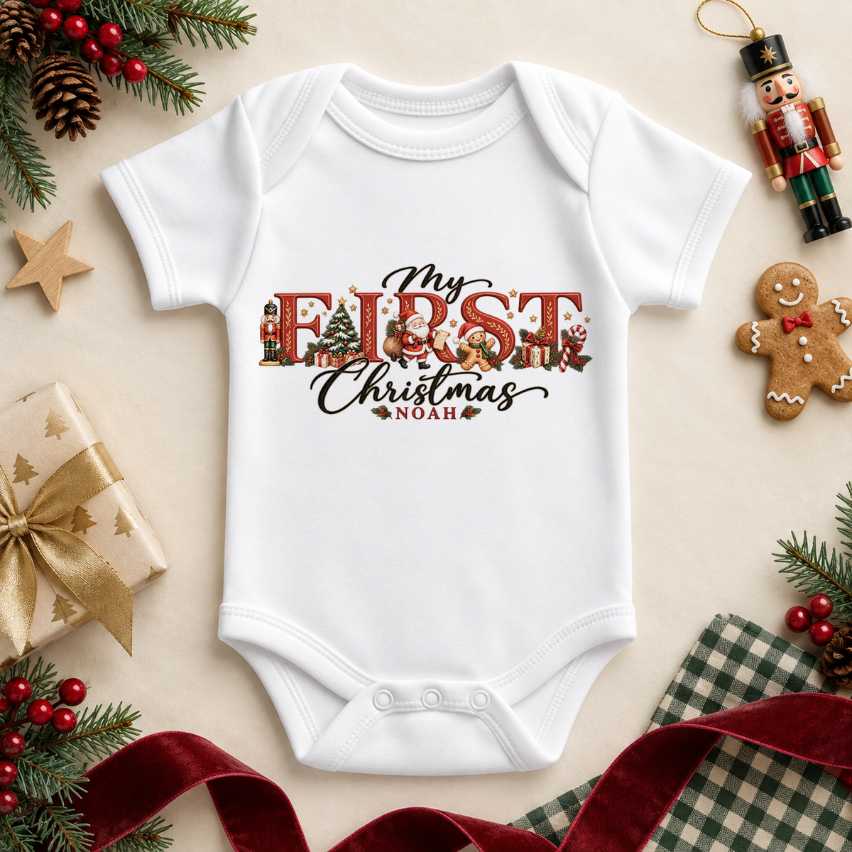White baby bodysuit. The print features red and gold festive lettering filled with little Christmas characters and decorations.