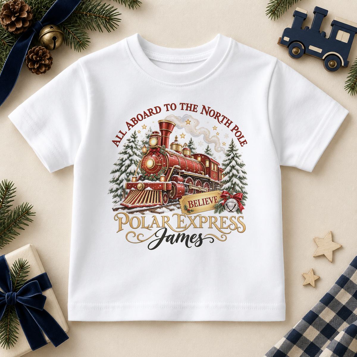 White children’s T-shirt. The print features a red and brass steam train with snowy trees, a gold ticket and a silver bell.