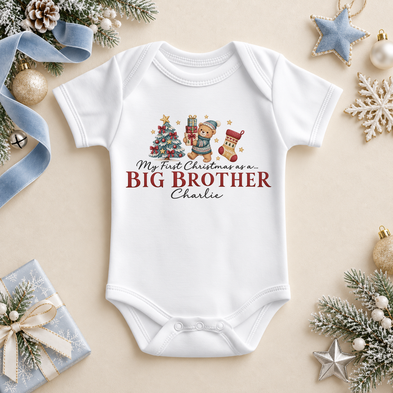 White baby bodysuit. The print features a teddy holding gifts beside a tree and stocking above Big Brother lettering.