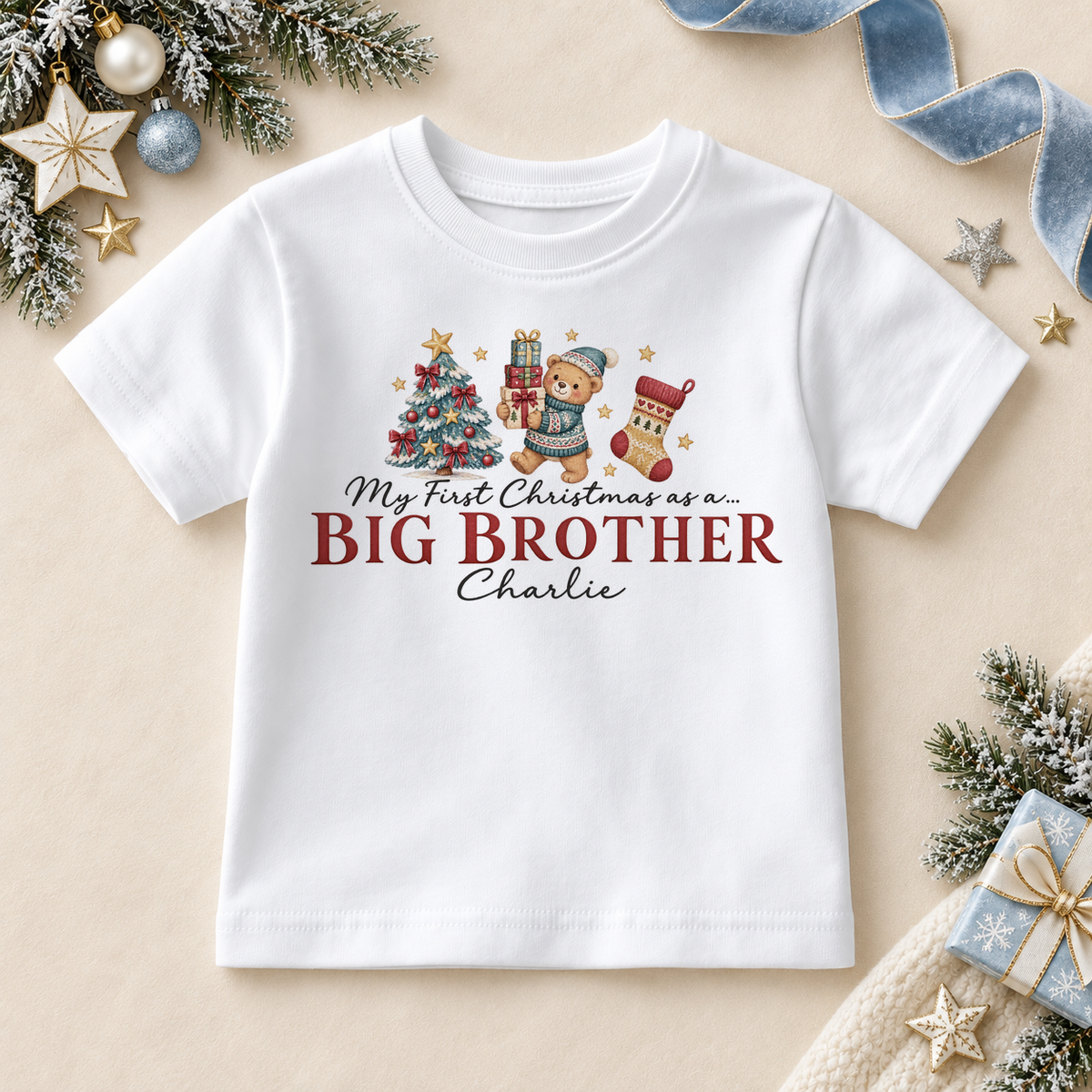 White children’s T-shirt. The print features a teddy holding gifts beside a tree and stocking above Big Brother lettering.