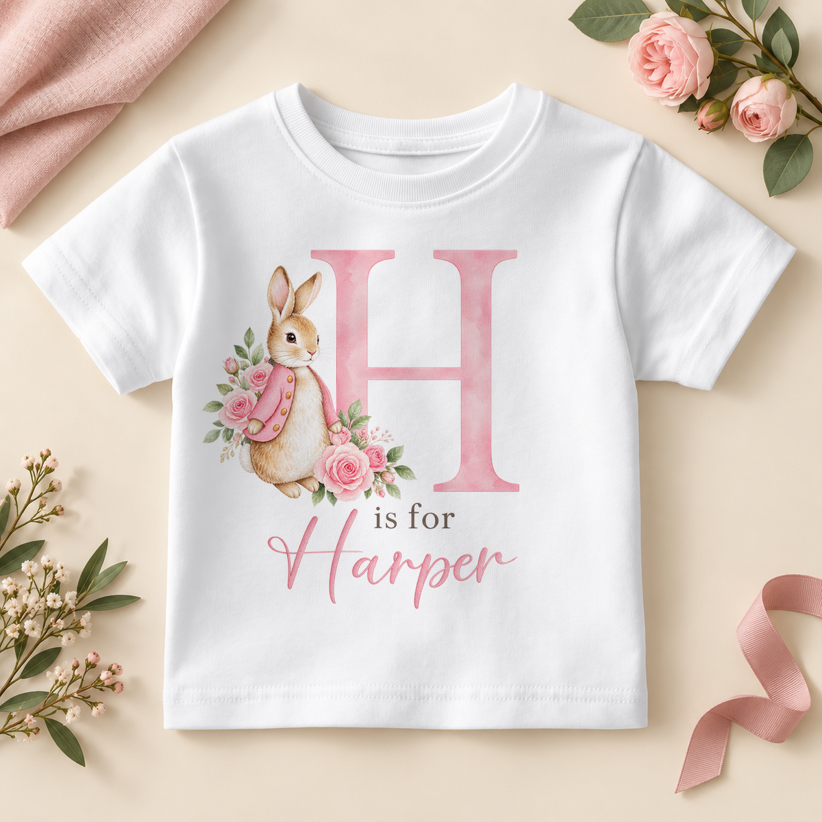White personalised kids T-shirt with a large pink H initial, a watercolour bunny in a pink jacket with pink roses and H is for Harper as an example name