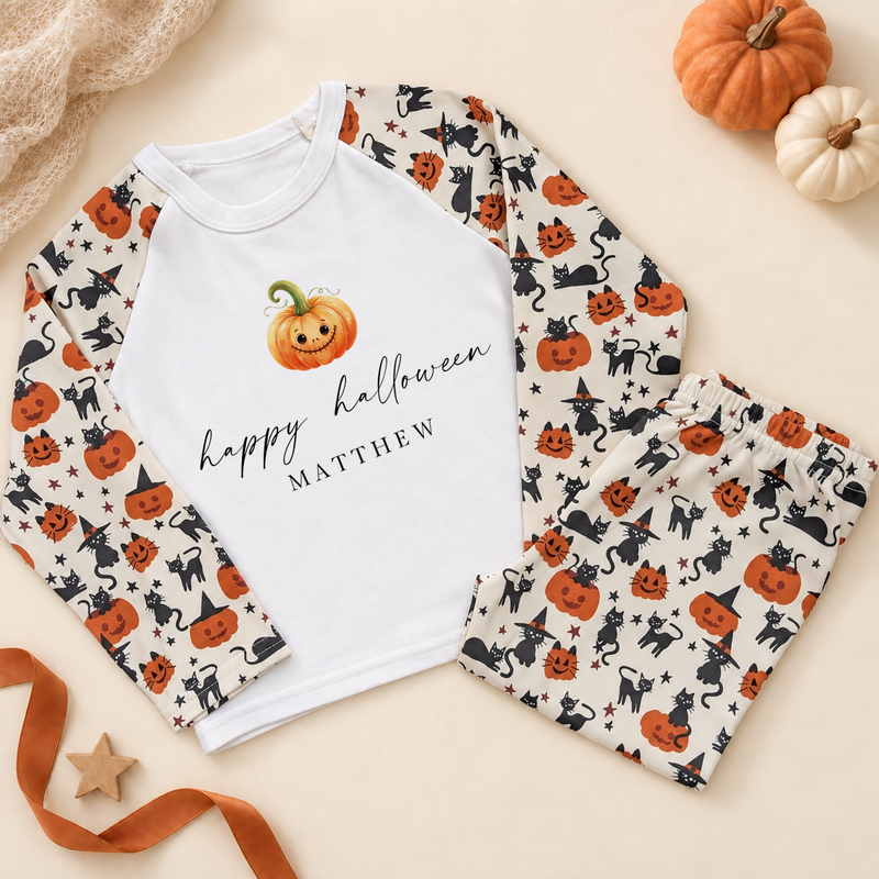 Personalised Halloween pyjama set with smiling pumpkin design, white top and pumpkin-and-cat patterned sleeves and trousers.