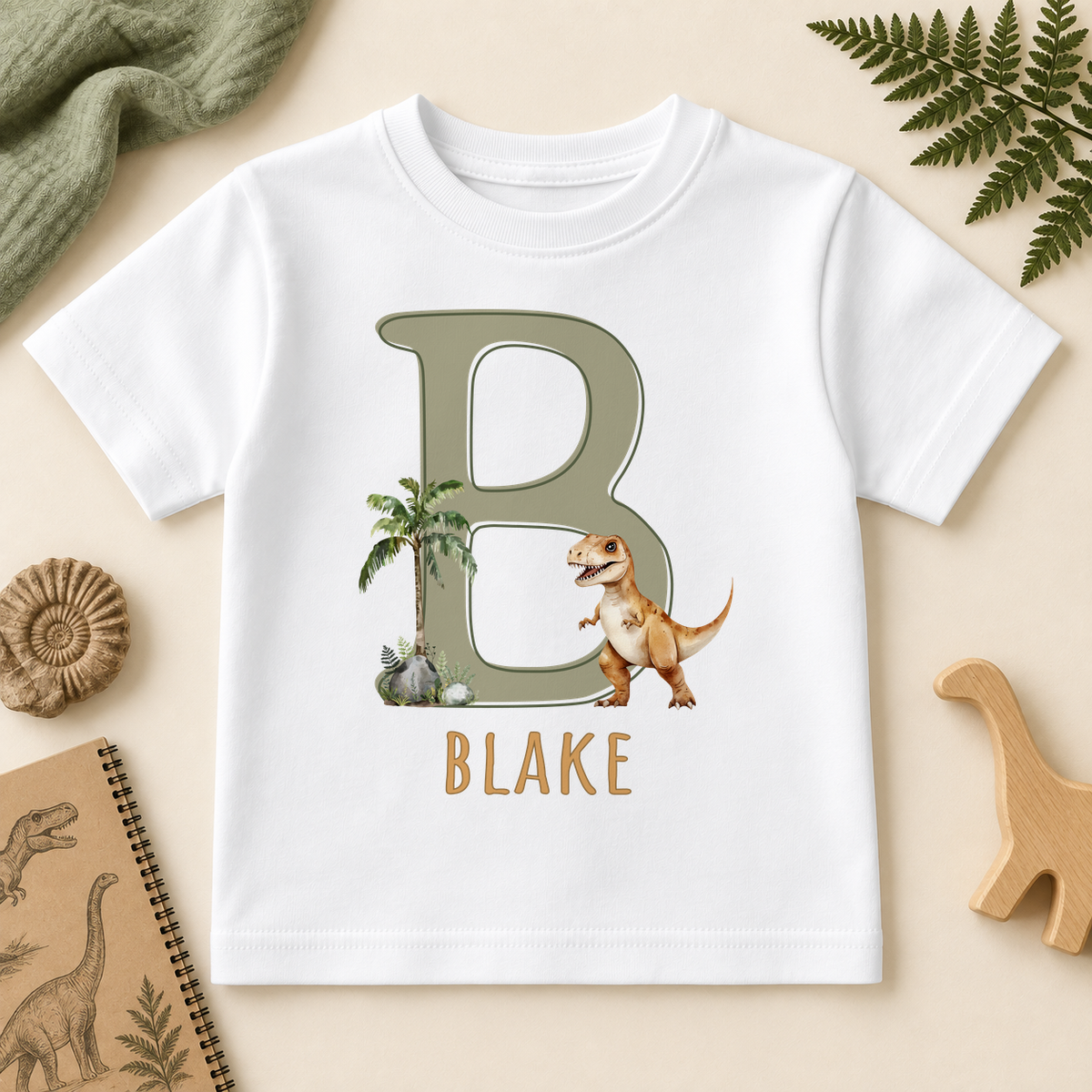 White T-Rex dinosaur T-shirt with sage initial B, palm tree and example name Blake.