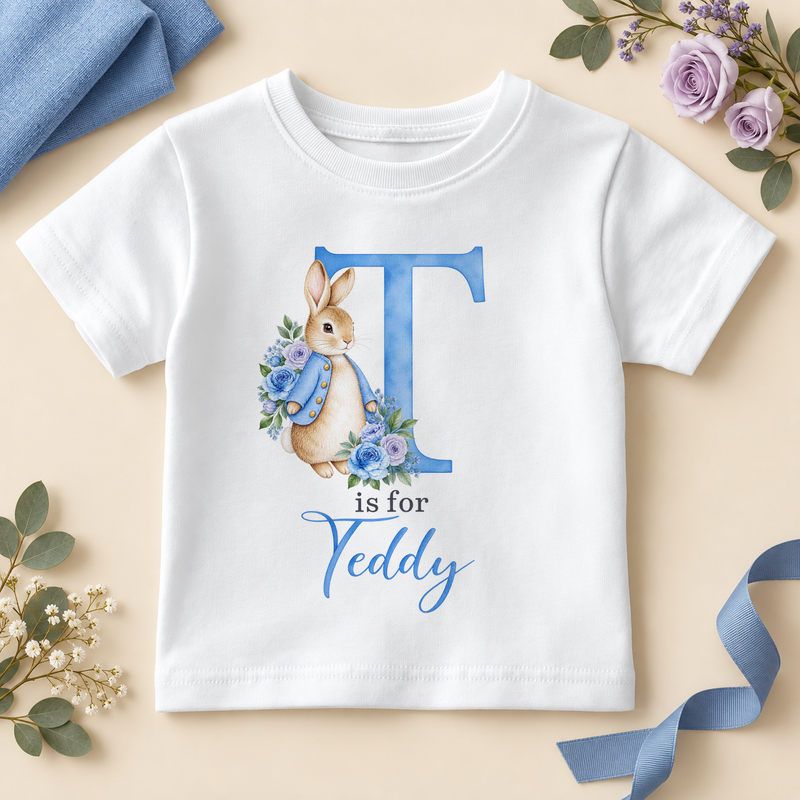 White personalised kids T-shirt with a large blue T initial, a watercolour bunny in a blue jacket with blue and lilac roses and T is for Teddy as an example name