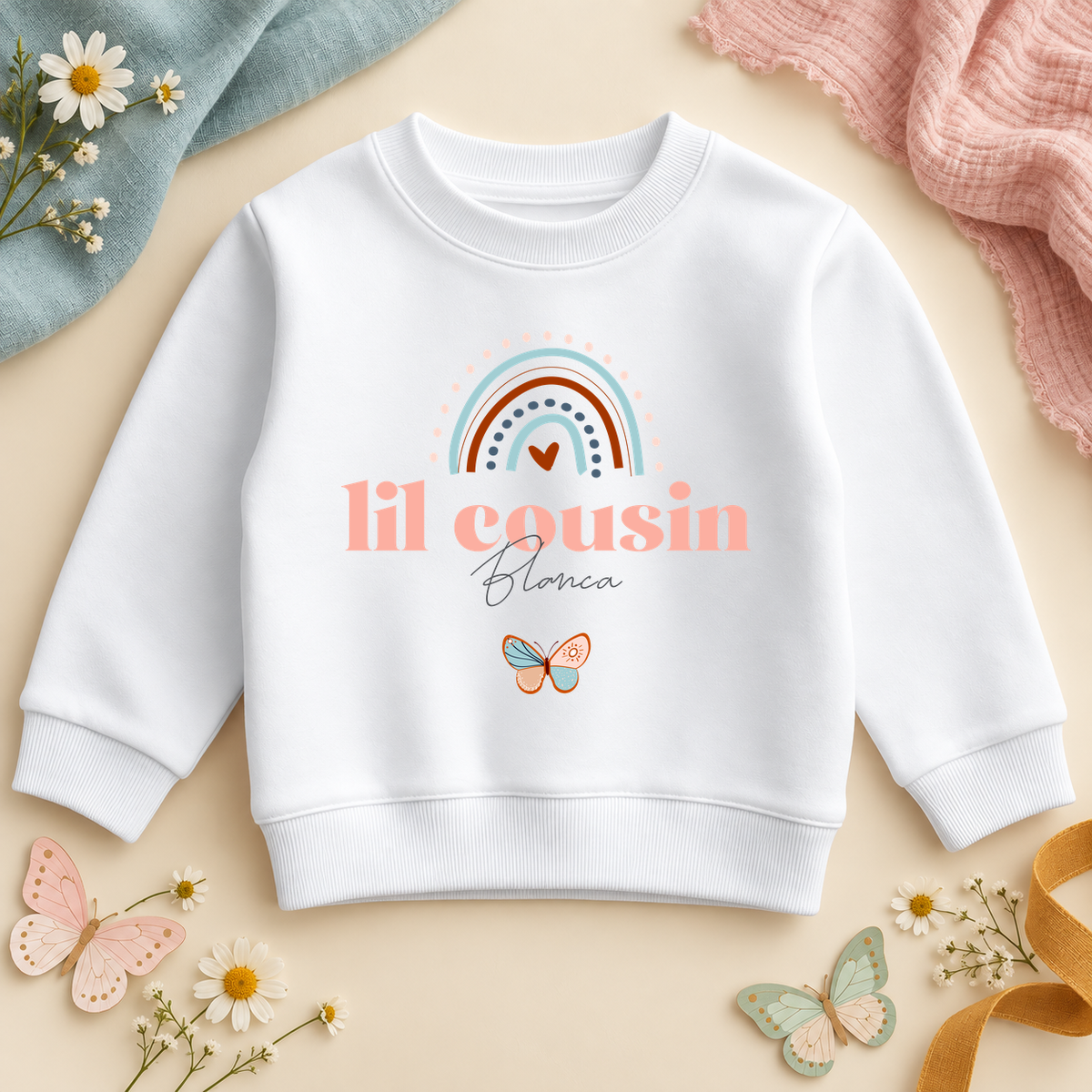 Lil Cousin rainbow butterfly white sweatshirt personalised with Blanca, pastel pink lettering and script name.
