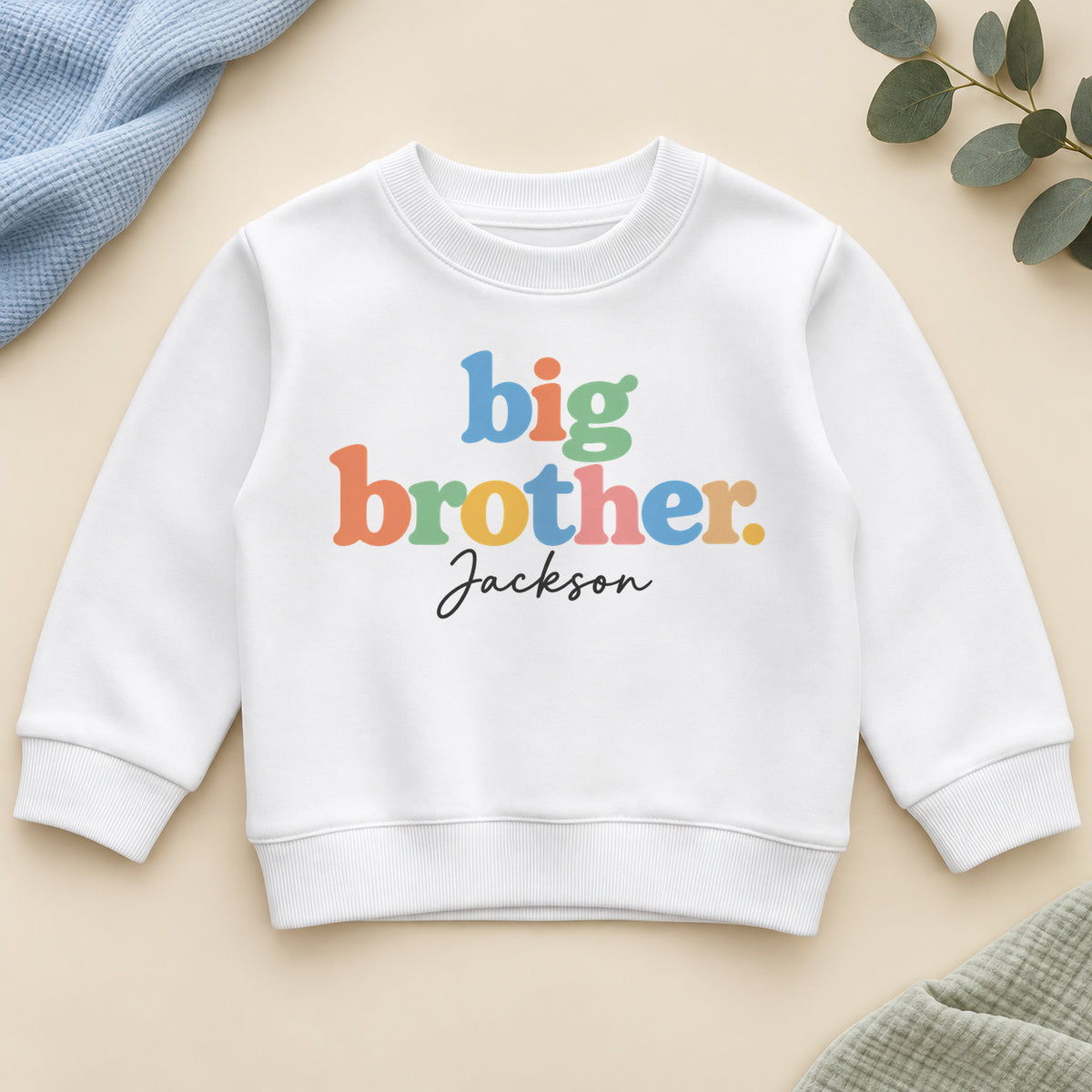 Personalised big brother sweatshirt with big brother in chunky pastel rainbow letters and an example name in black script on a white crew neck sweatshirt