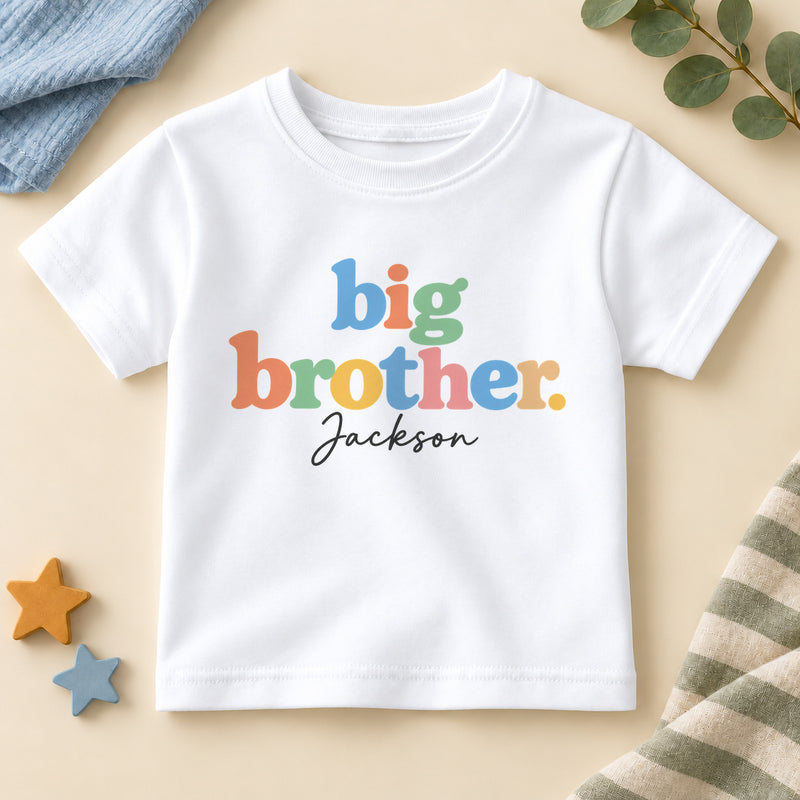 Personalised big brother T-shirt with big brother in chunky pastel rainbow letters and an example name in black script on a white crew neck tee