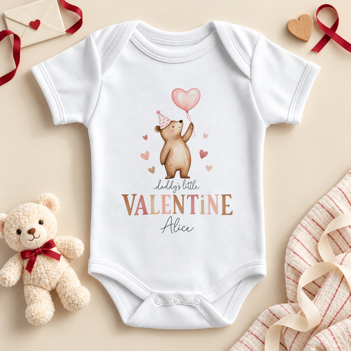 Personalised Daddy's little valentine baby bodysuit: a white baby vest with a teddy bear in a pink party hat holding a heart balloon, brown and pink lettering and an example name