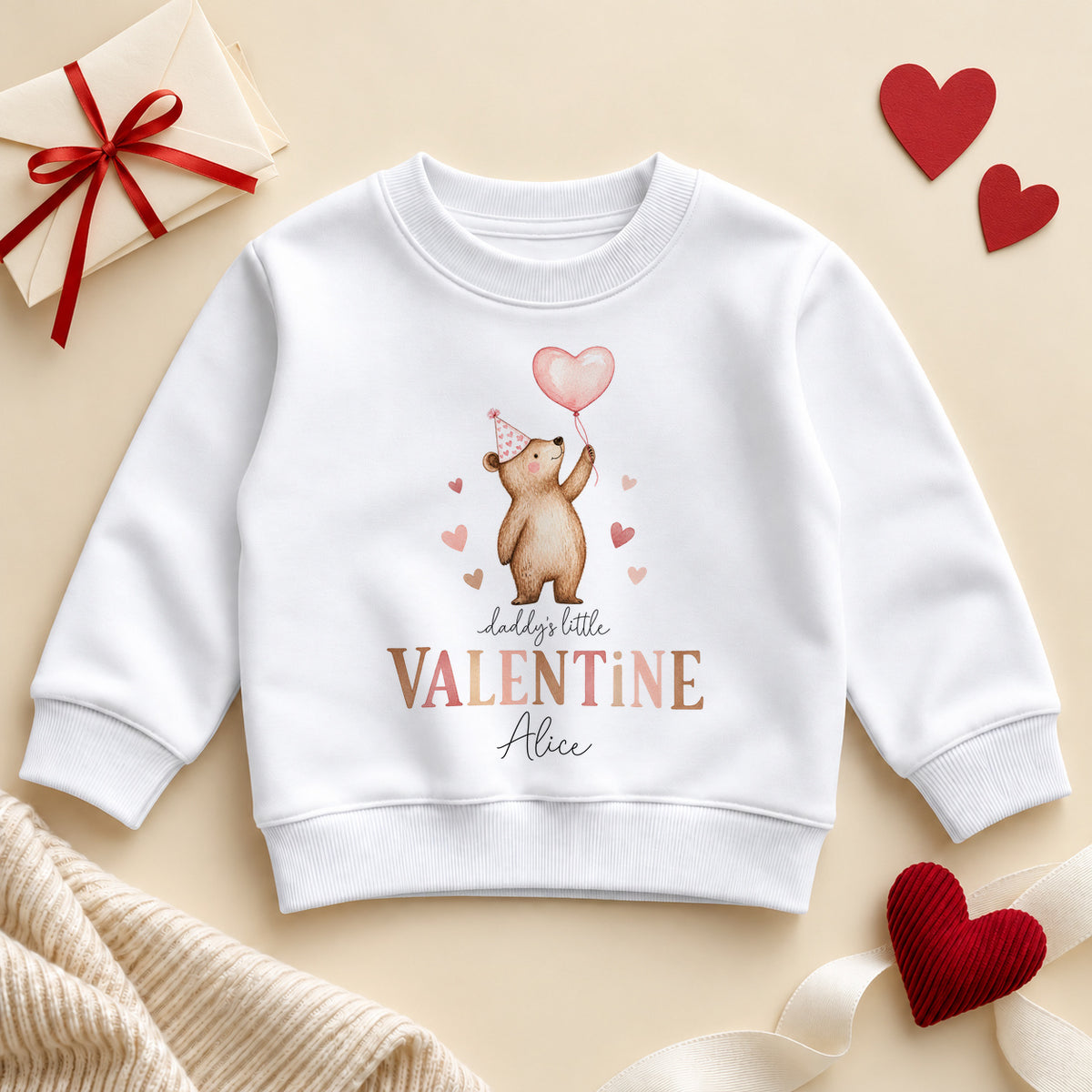 Personalised Daddy's little valentine toddler sweatshirt: a white jumper with a teddy bear in a pink party hat holding a heart balloon, brown and pink lettering and an example name