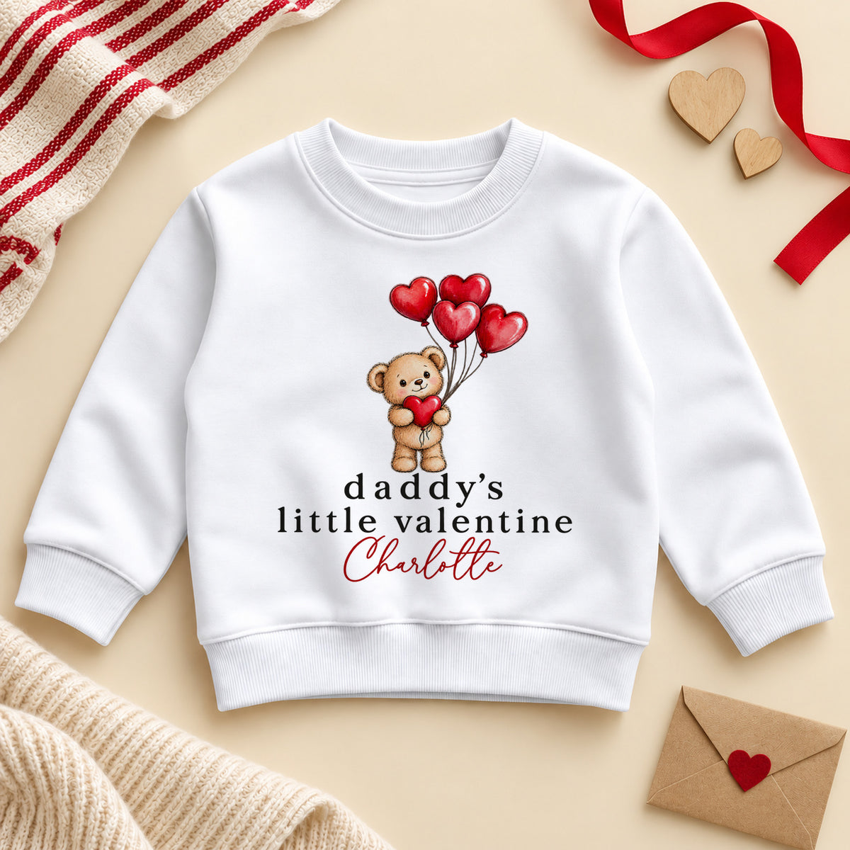 Personalised Daddy's little valentine toddler sweatshirt: a white jumper with a teddy bear holding red heart balloons and an example name in red script
