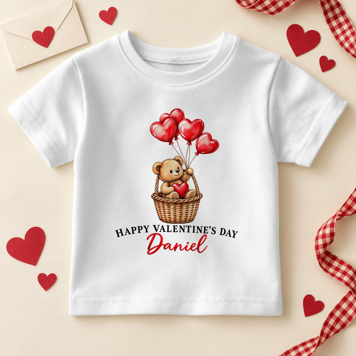 Personalised Happy Valentine's Day kids T-shirt: a white tee with a teddy bear in a wicker basket holding red heart balloons and an example name