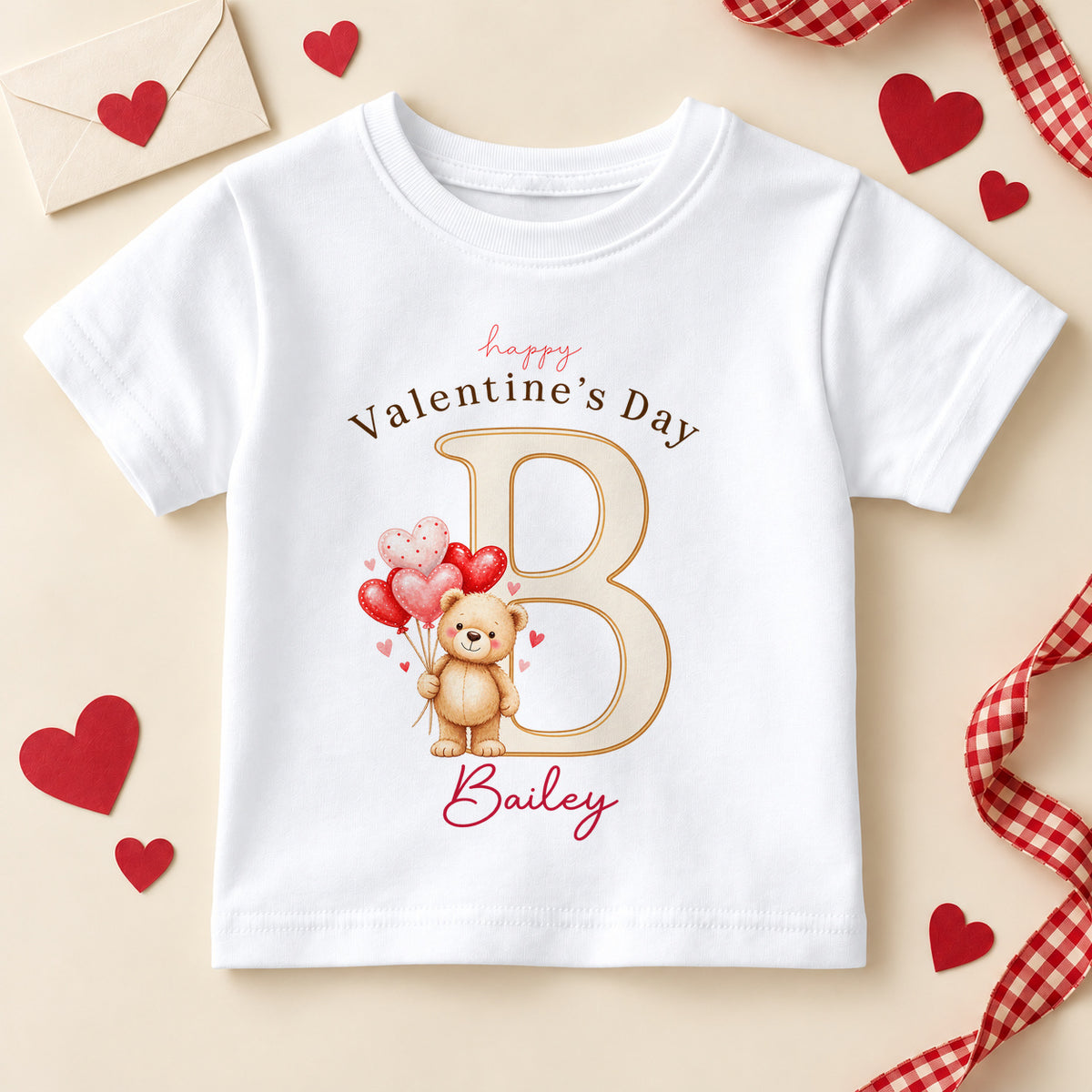 Personalised Happy Valentine's Day kids T-shirt: a white tee with a teddy bear holding heart balloons, a large initial letter and an example name