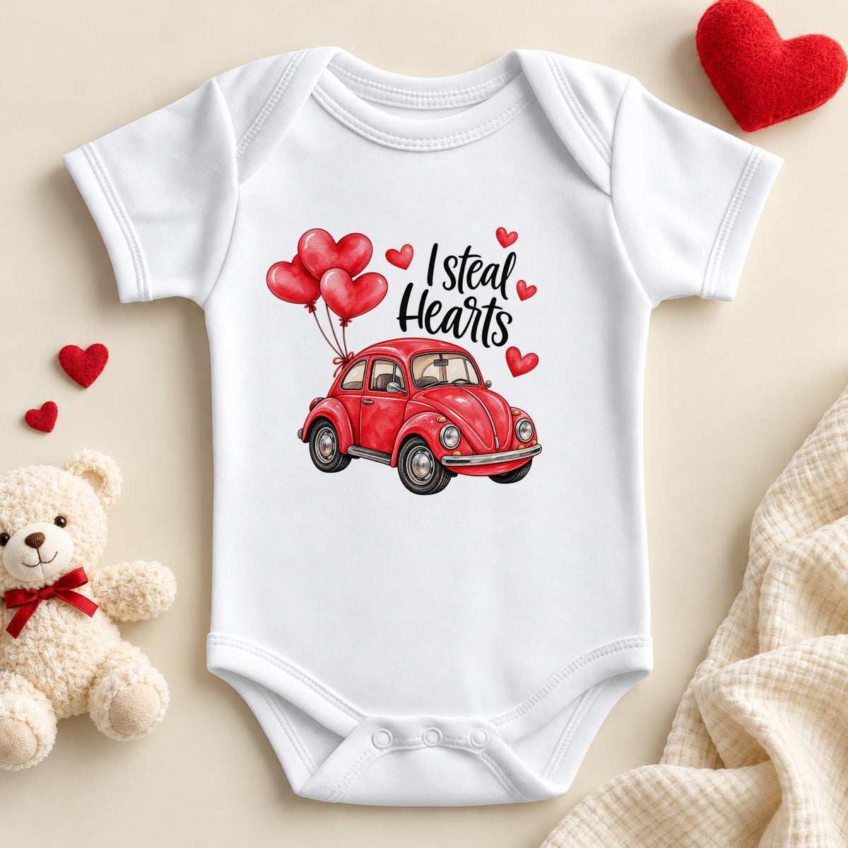 I Steal Hearts baby bodysuit: a white baby vest with black script and a red vintage car carrying red heart balloons