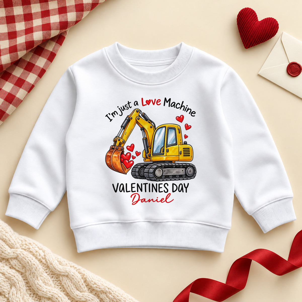 Personalised I'm just a Love Machine toddler sweatshirt: a white jumper with a yellow digger scooping red hearts, VALENTINES DAY capitals and an example name in red script