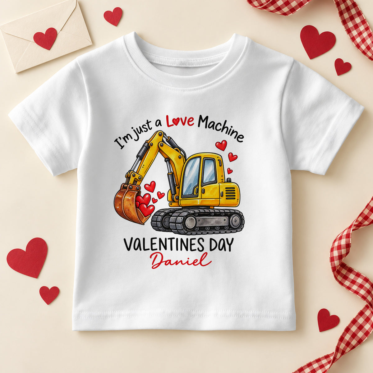 Personalised I'm just a Love Machine kids T-shirt: a white tee with a yellow digger scooping red hearts, VALENTINES DAY capitals and an example name in red script