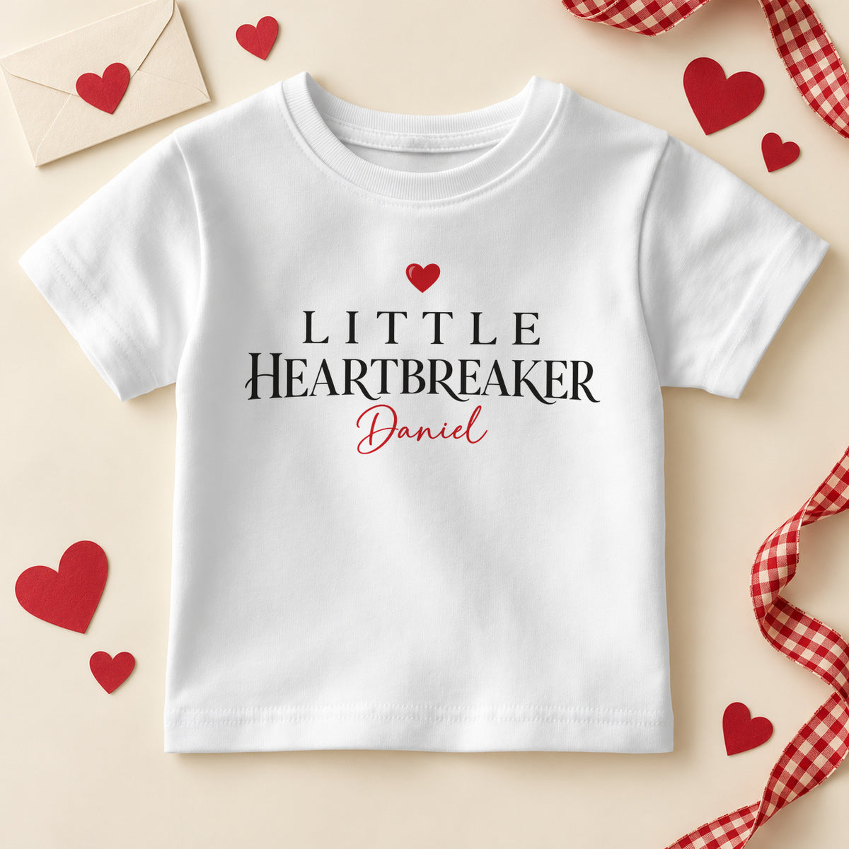 Personalised Little Heartbreaker kids T-shirt: a white tee with black serif capitals, a red heart and an example name in red script