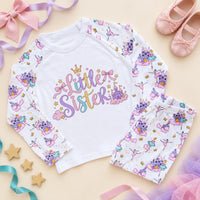 Little sister pyjamas with pastel script lettering, a gold crown, pink bows and a fairy castle on a white chest, with ballerina and princess castle print raglan sleeves and trousers