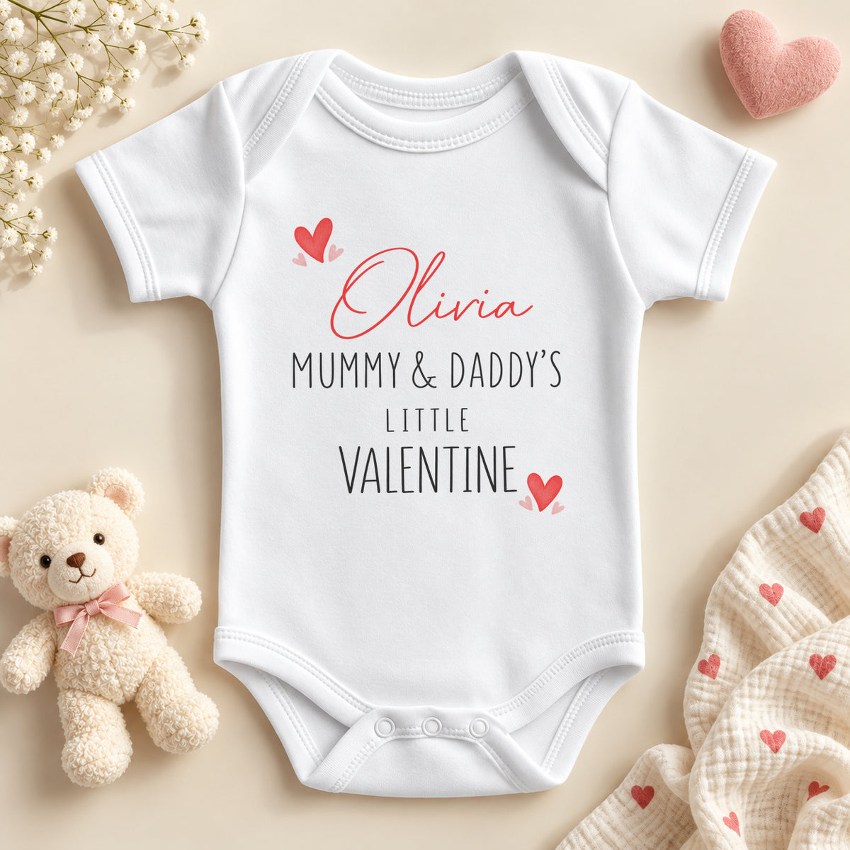 Personalised Mummy and Daddy's little valentine baby bodysuit: a white baby vest with an example name in red script, black capitals and little red hearts