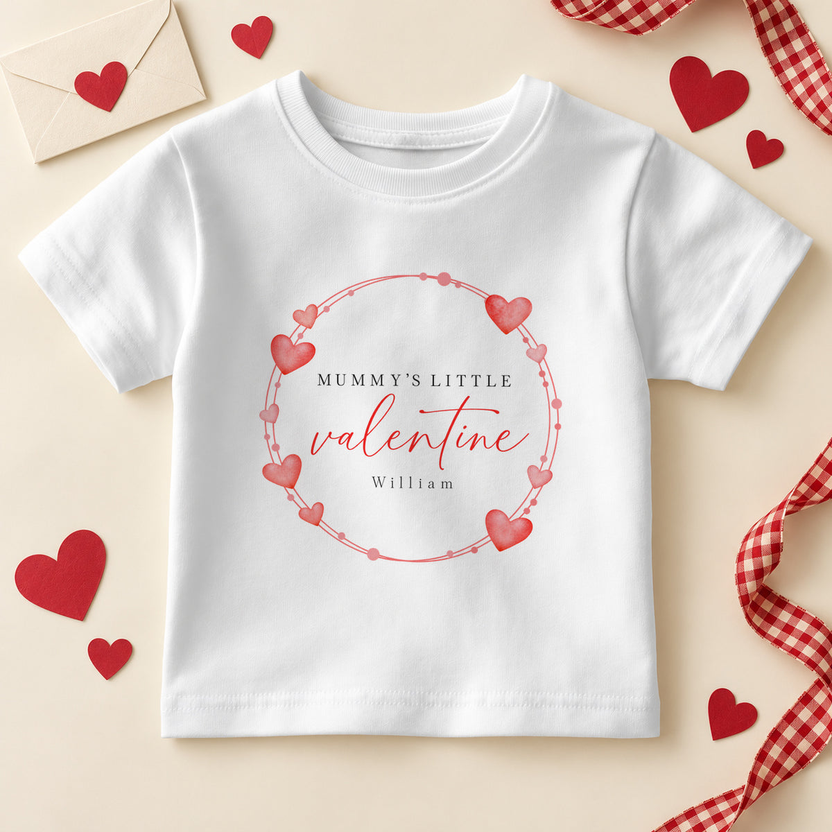 Personalised Mummy's little valentine kids T-shirt: a white tee with a wreath of red and pink hearts, red script and an example name