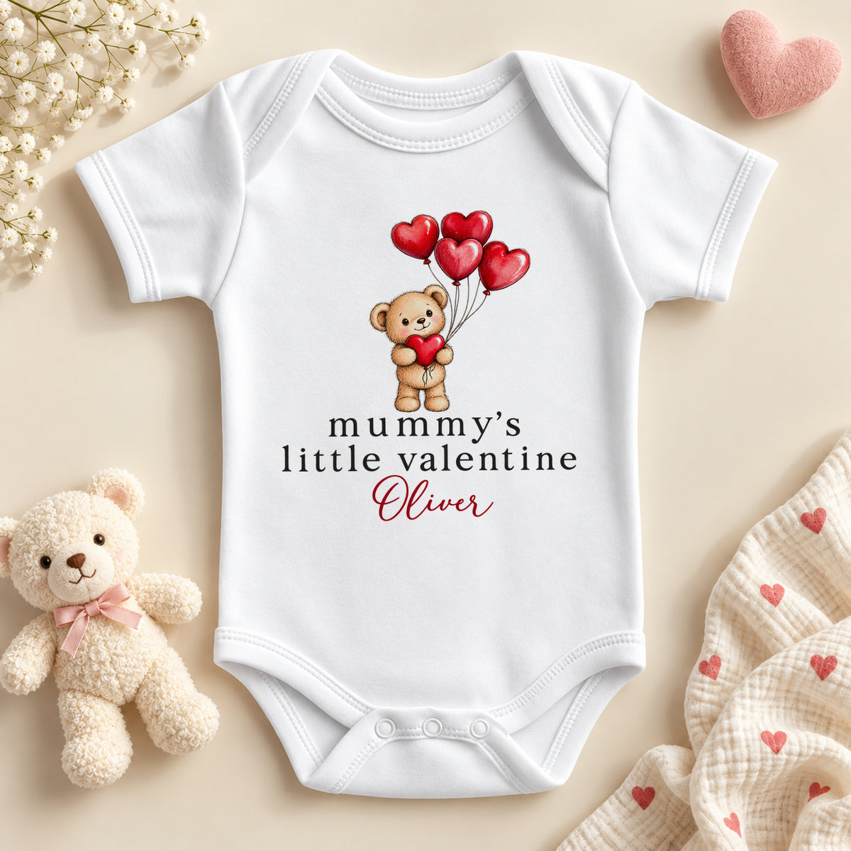 Personalised Mummy's little valentine baby bodysuit: a white baby vest with a teddy bear holding red heart balloons and an example name in red script