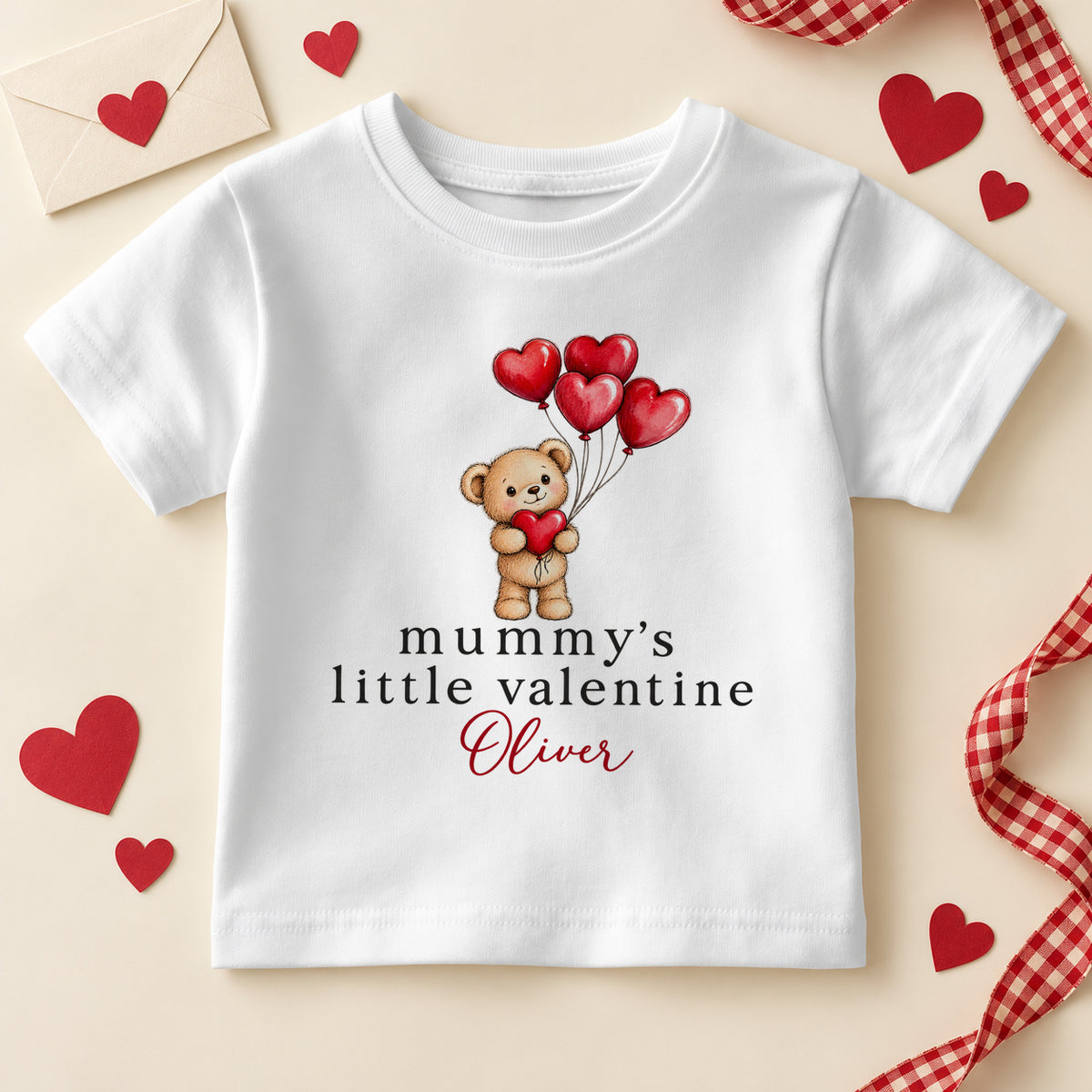 Personalised Mummy's little valentine kids T-shirt: a white tee with a teddy bear holding red heart balloons and an example name in red script