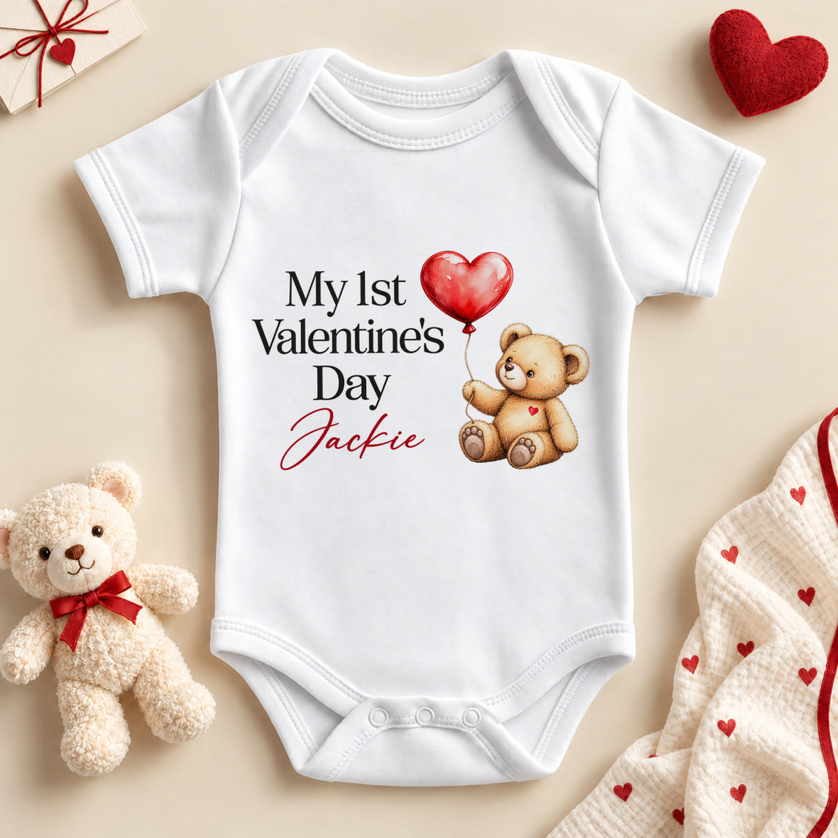 Personalised My 1st Valentine's Day baby bodysuit: a white baby vest with black serif lettering, a teddy bear holding a red heart balloon and an example name