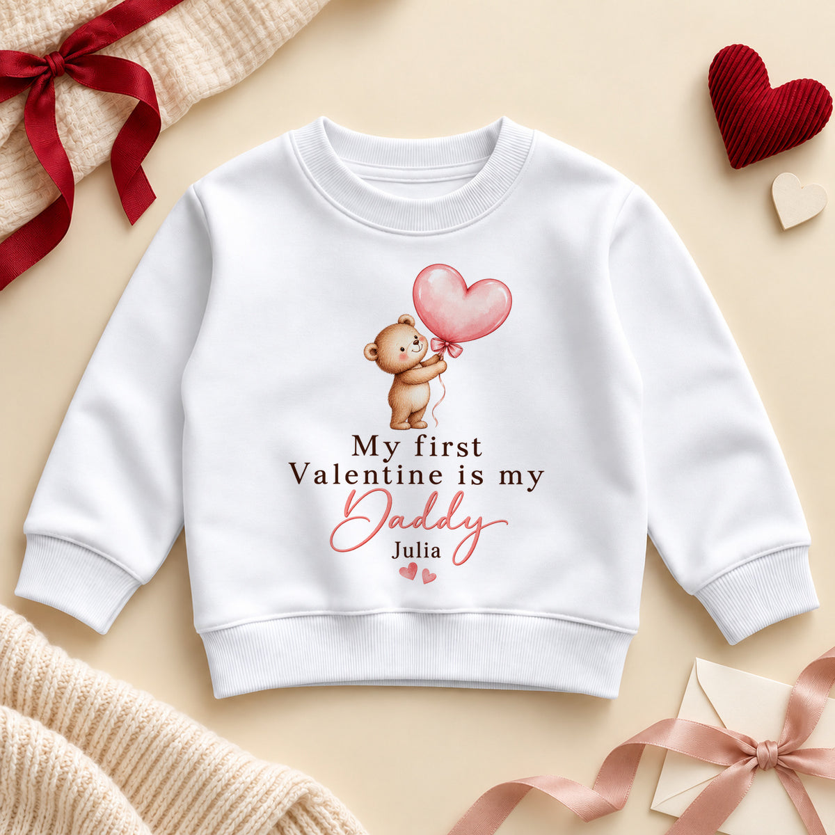 Personalised my first Valentine is my Daddy toddler sweatshirt: a white jumper with a teddy bear holding a pink heart balloon, pink script and an example name