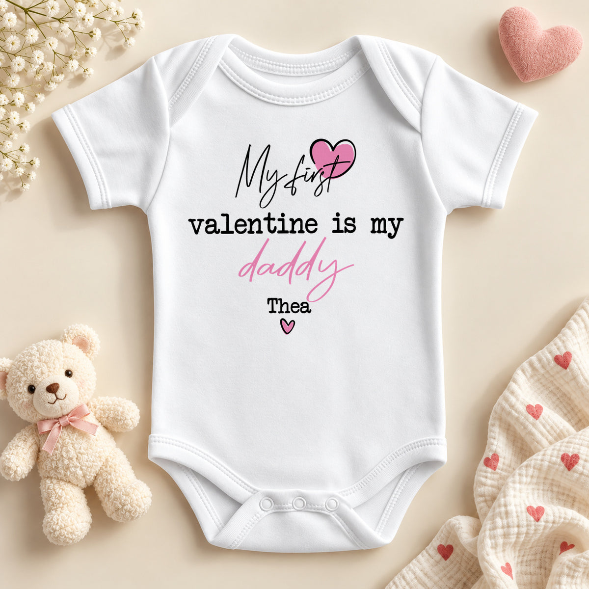 Personalised my first Valentine is my Daddy baby bodysuit: a white baby vest with script and typewriter lettering, a pink heart and an example name