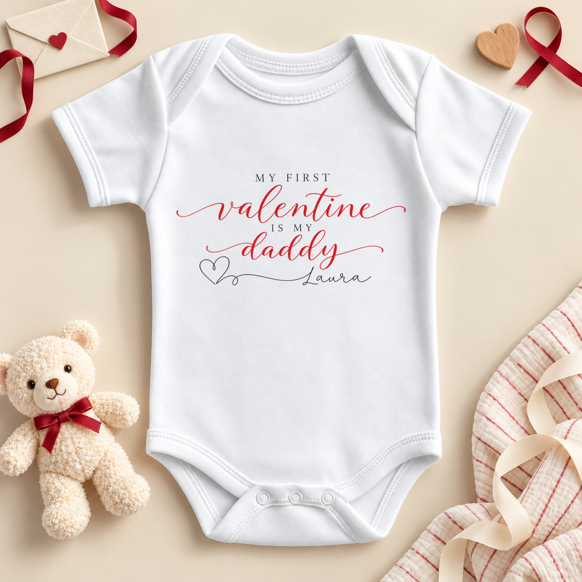 Personalised my first Valentine is my Daddy baby bodysuit: a white baby vest with red script, small black capitals and a heart line to an example name