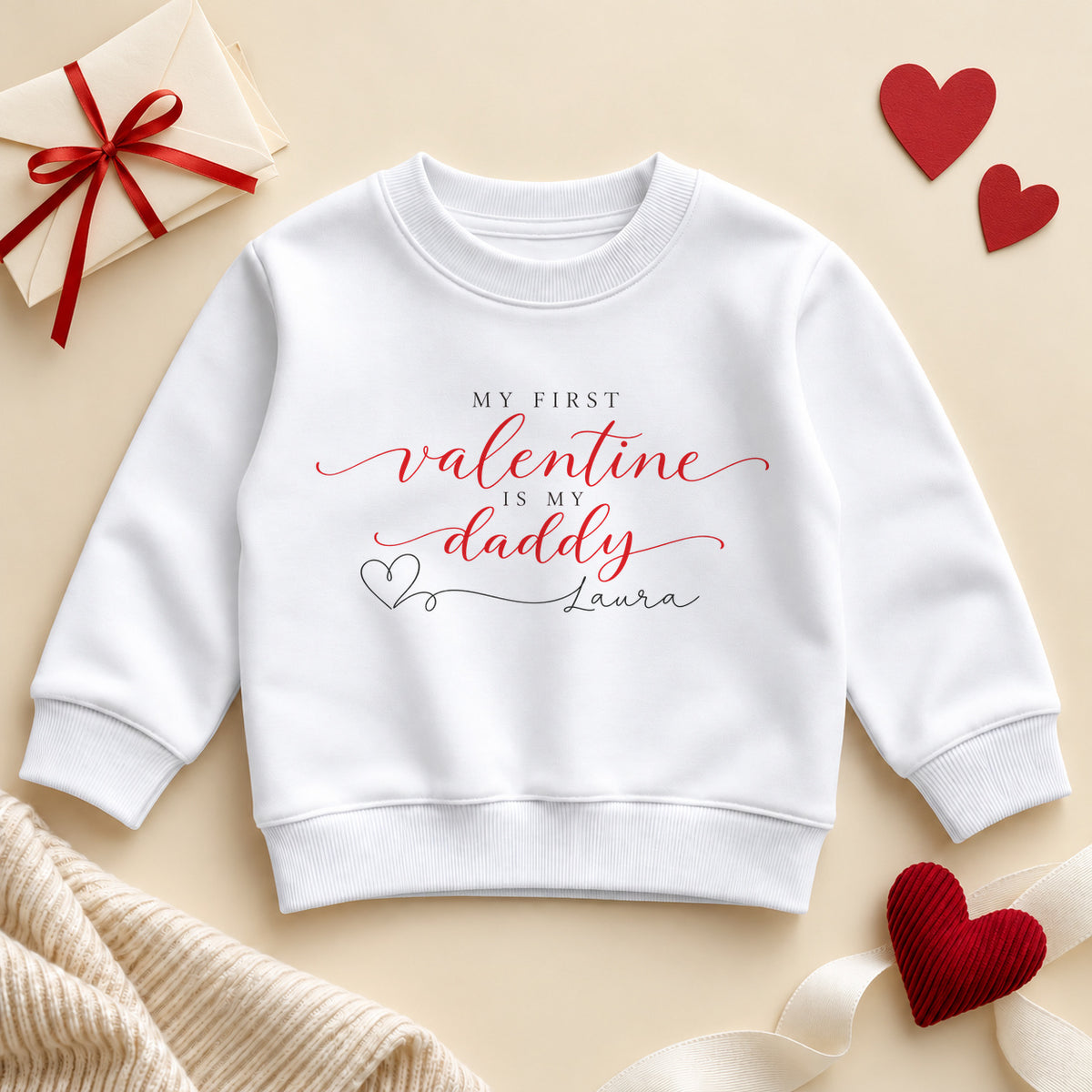 Personalised my first Valentine is my Daddy toddler sweatshirt: a white jumper with red script, small black capitals and a heart line to an example name
