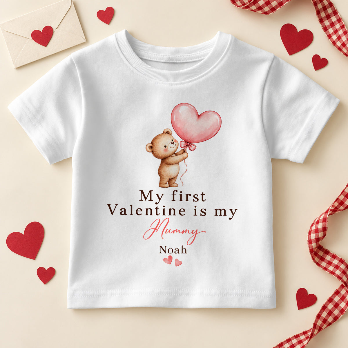 Personalised my first Valentine is my Mummy kids T-shirt: a white tee with a teddy bear holding a pink heart balloon, pink script and an example name