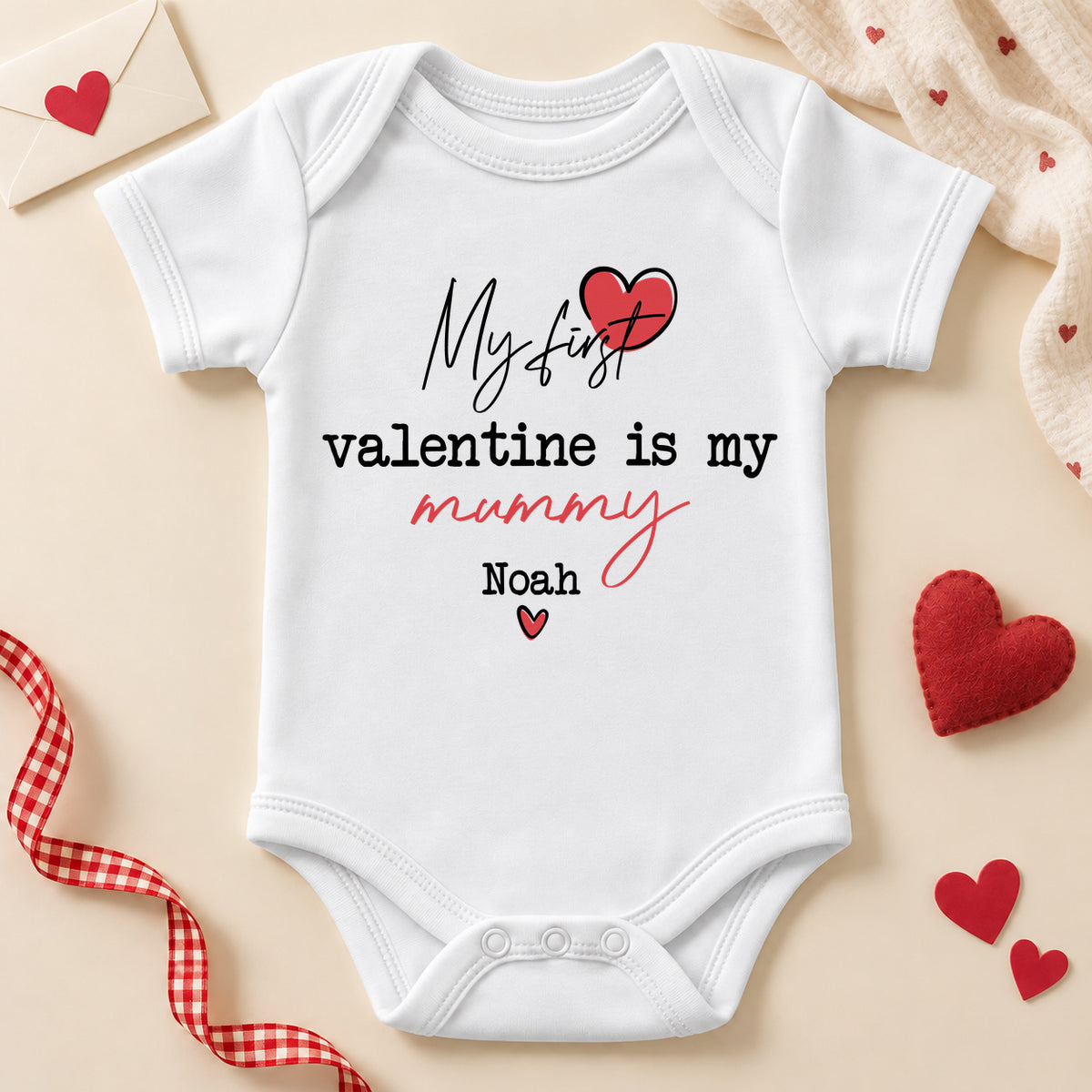 Personalised my first Valentine is my Mummy baby bodysuit: a white baby vest with script and typewriter lettering, a red heart and an example name
