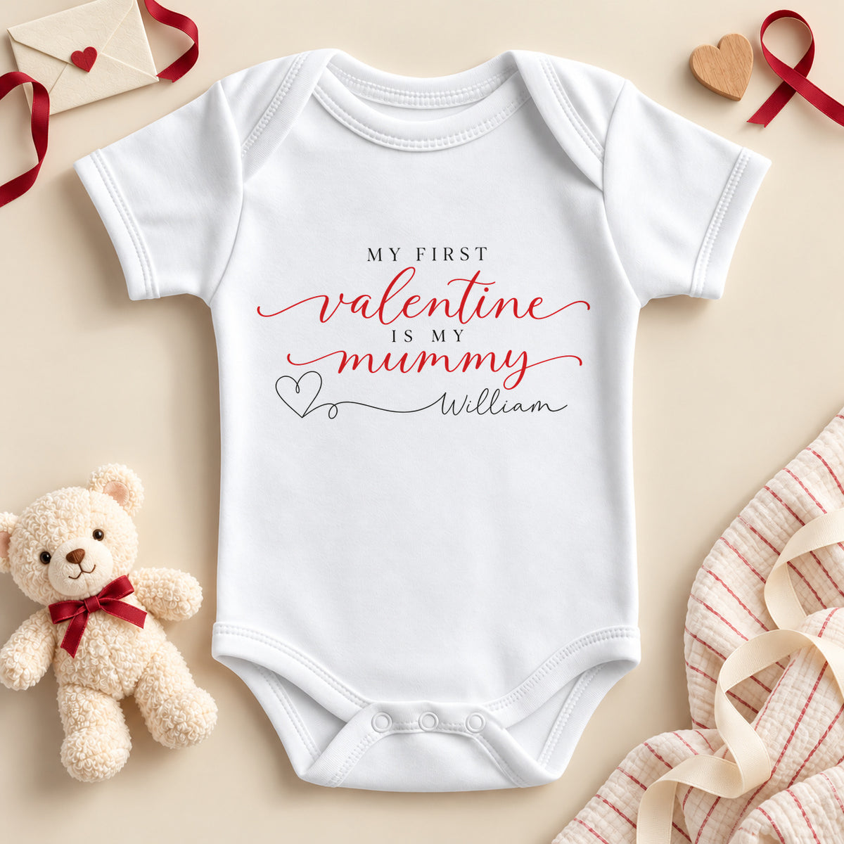 Personalised my first Valentine is my Mummy baby bodysuit: a white baby vest with red script, small black capitals and a heart line to an example name