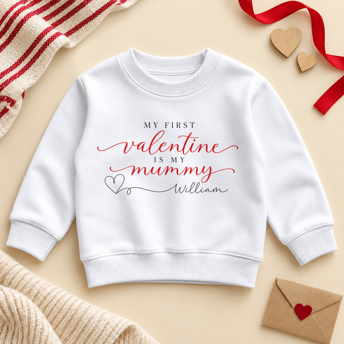 Personalised my first Valentine is my Mummy toddler sweatshirt: a white jumper with red script, small black capitals and a heart line to an example name