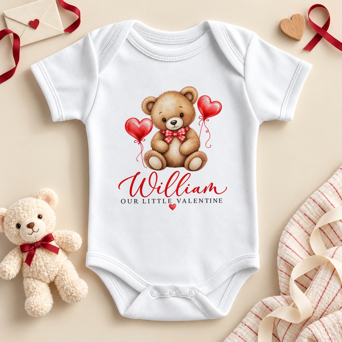 Personalised Our Little Valentine baby bodysuit: a white baby vest with a teddy bear in a red bow tie between two red heart balloons and an example name in red script