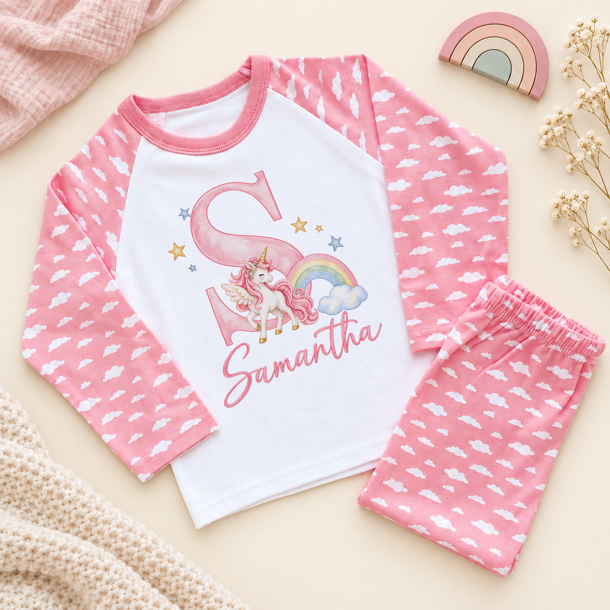 Pink cloud pyjama set with a watercolour unicorn, rainbow, initial S and Samantha example name on a white cotton top.