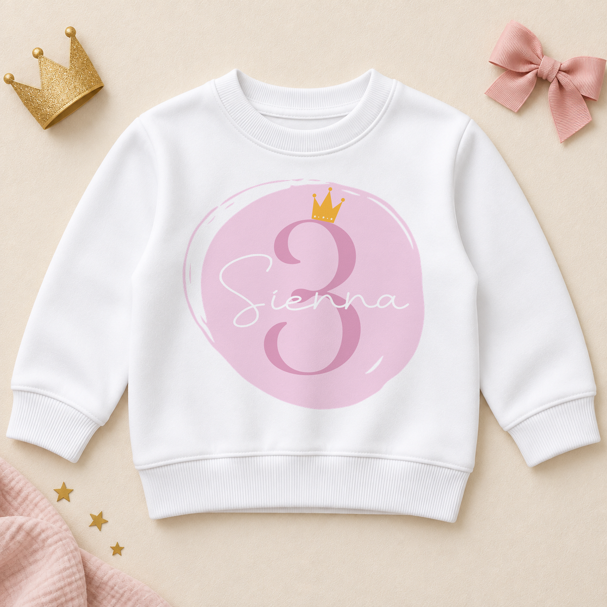 White personalised third birthday kids sweatshirt with pink number three, brushstroke circle, gold-coloured crown and Sienna example name in white script.